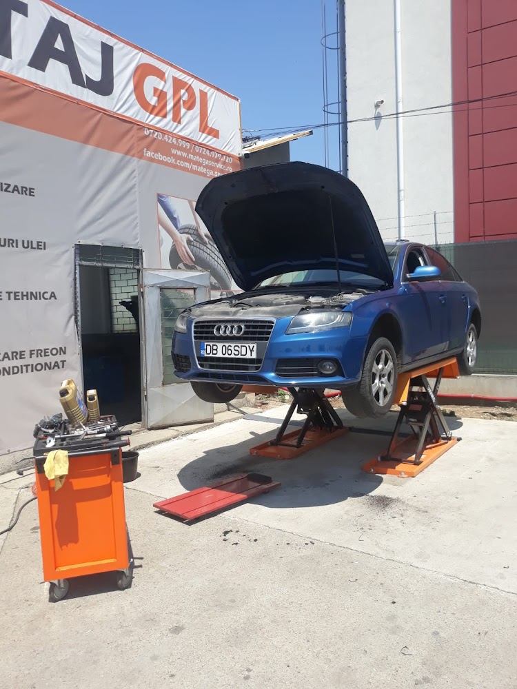 Autoturism ridicat pe elevator la Matega Service Auto, în fața panoului cu servicii de montaj GPL